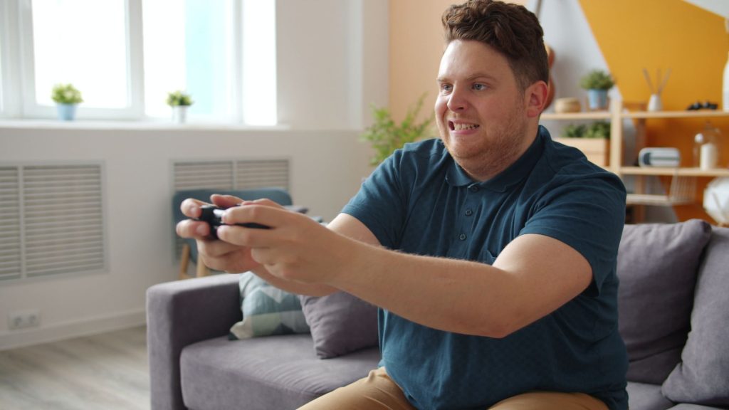 Man intensely focused on playing video games in a comfortable living room setting. — Bet Series FAQs: Everything You Need to