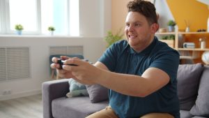 Man intensely focused on playing video games in a comfortable living room setting. — Bet Series FAQs: Everything You Need to
