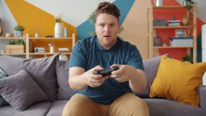 A young man intensely playing video games in a modern living room setting. — Elevating Your Rimba Slot Experience: Advanced T