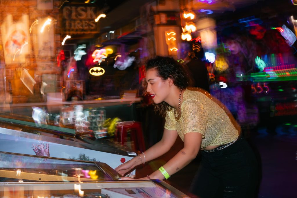 Young woman enjoying a night out playing pinball in an energetic arcade setting. — High-Quality Casino Sites with Proven Trac