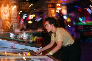 Young woman enjoying a night out playing pinball in an energetic arcade setting. — High-Quality Casino Sites with Proven Trac