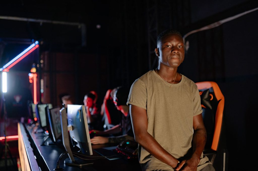A young gamer in a dimly lit gaming arena, surrounded by teammates. — Internet Casino- Gambles And Earns Actual Money Rapidly