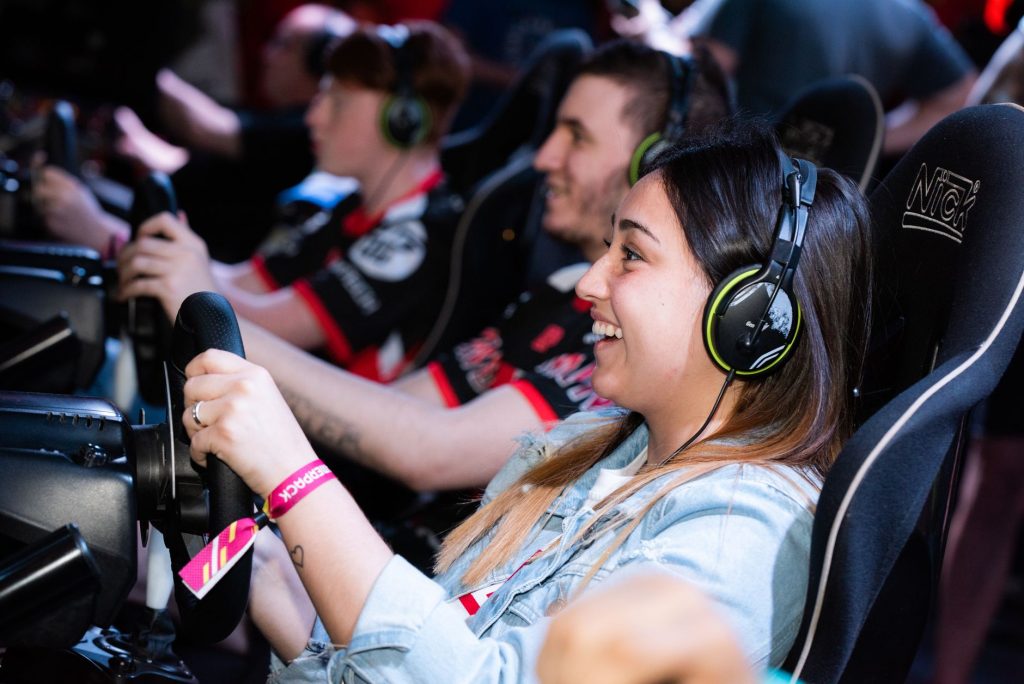 A group of people enjoying an immersive gaming experience at an e-sports center with headphones and steering wheels. — Koitot