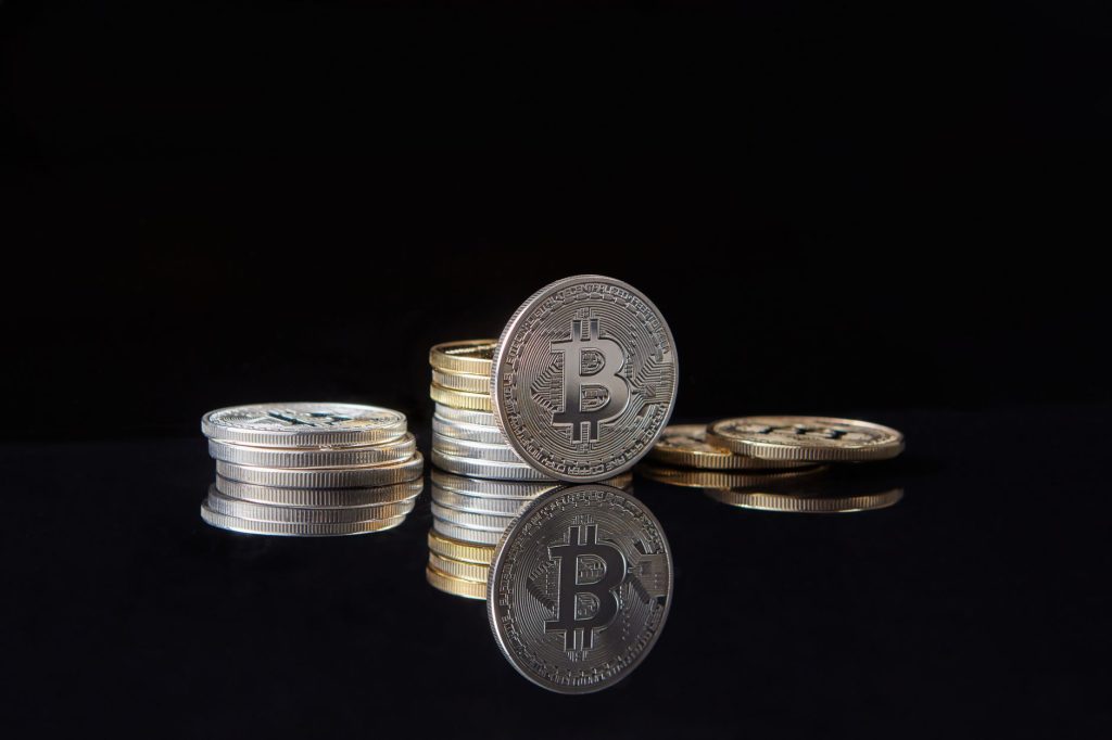 Silver bitcoins stacked on a reflective surface with a dark background, symbolizing cryptocurrency and digital wealth. — Navi