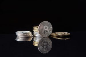 Silver bitcoins stacked on a reflective surface with a dark background, symbolizing cryptocurrency and digital wealth. — Navi