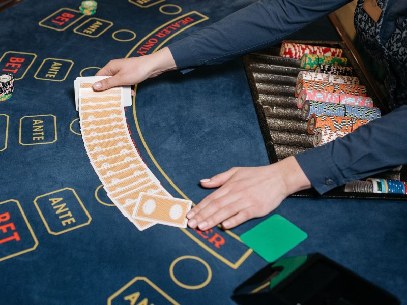 A casino dealer skillfully spreads playing cards on a gaming table, surrounded by colorful poker chips. — Rewards that may be