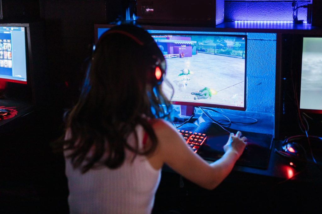 Female gamer focused on playing a competitive online game with RGB keyboard and headphones. — Soccer Betting-Priority of Gene