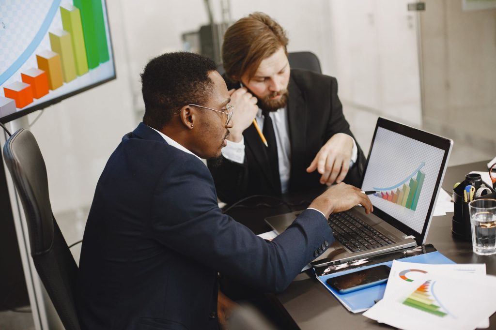 Two business professionals working on growth charts using laptop in an office setting. — Ensuring Fair Play: The Impo