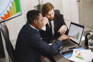 Two business professionals working on growth charts using laptop in an office setting. — Ensuring Fair Play: The Impo