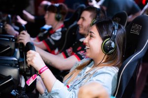 A group of people enjoying an immersive gaming experience at an e-sports center with headphones and steering wheels. —