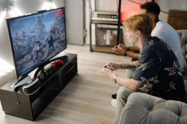 Two friends immersed in playing video games together in a cozy living room. — Win it Big with UFA Games Roulette