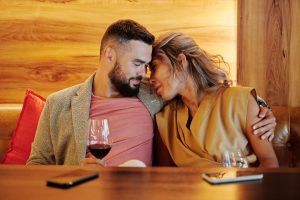 A couple shares an intimate moment with wine glasses at a cozy restaurant setting. — The Ultimate Guide To Online Dating