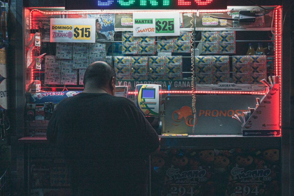 A man purchasing a lottery ticket at an illuminated kiosk in Mexico City, highlighting risk and hope. — Trusted Online Lotter