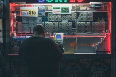 A man purchasing a lottery ticket at an illuminated kiosk in Mexico City, highlighting risk and hope. — Trusted Online Lotter