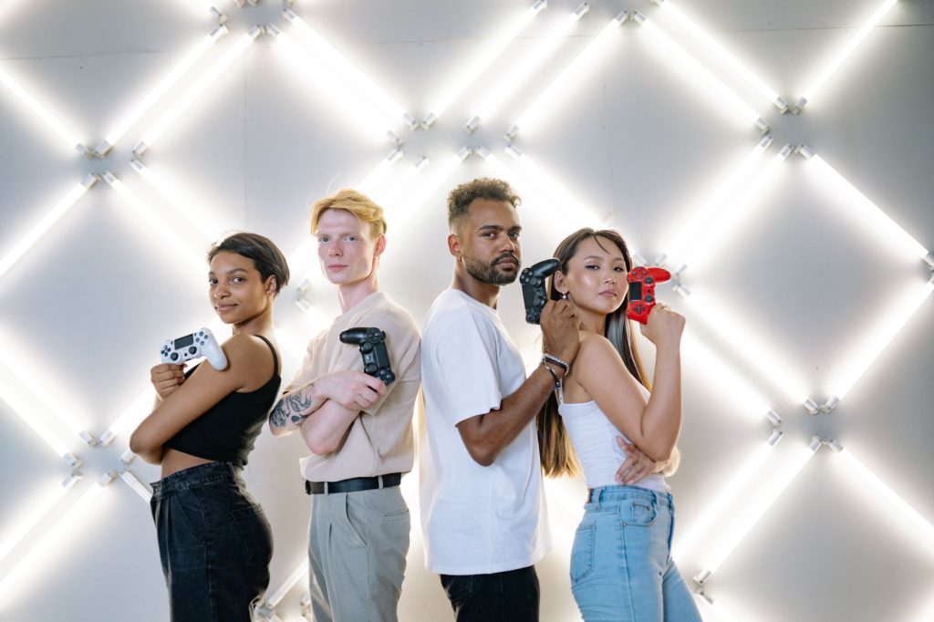 Four diverse friends posing confidently with game controllers against a modern LED backdrop. — UFA656 Live Gaming Platform Ov