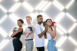 Four diverse friends posing confidently with game controllers against a modern LED backdrop. — UFA656 Live Gaming Platform Ov