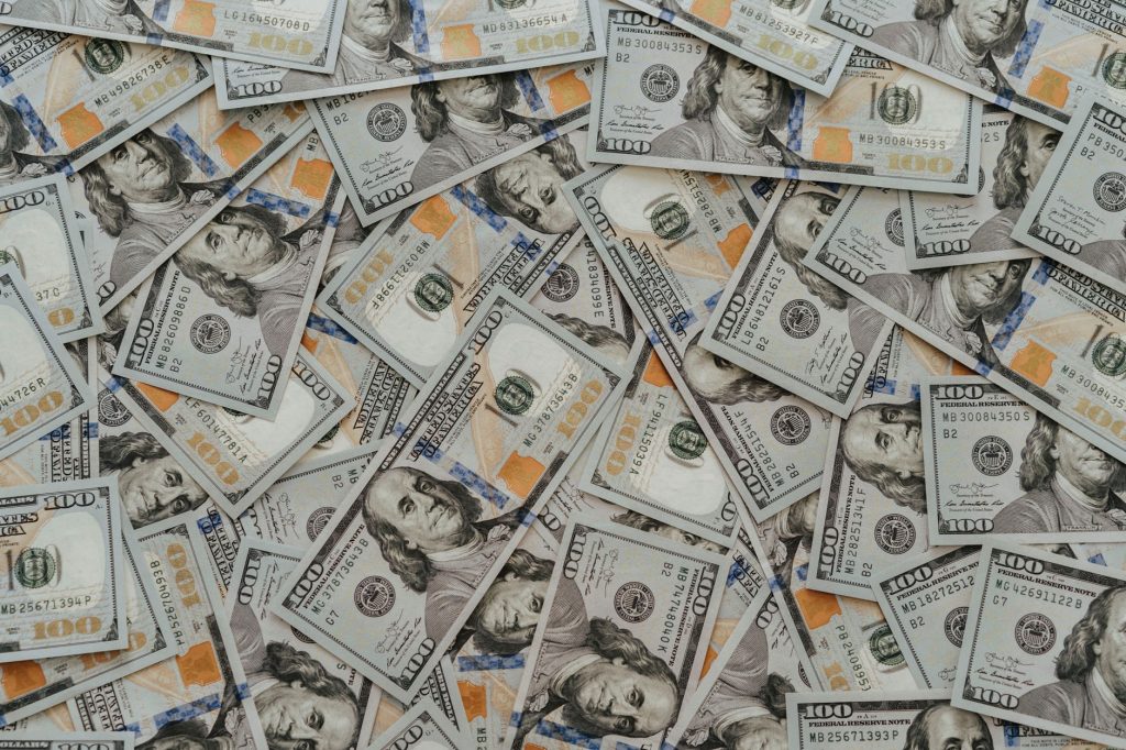 US hundred dollar bills scattered in abundance creating a financial backdrop. — UFABET Can Give Your Surety For Generating Re
