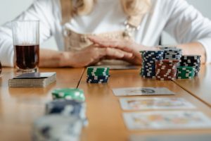 Senior woman playing poker with cards and chips on a wooden table indoors. — What advantages a novice might have online footb