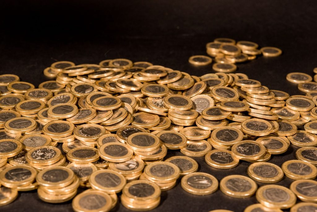 Close-up of a pile of Euro coins scattered on a black surface, representing wealth and finance. — Would you like to create a